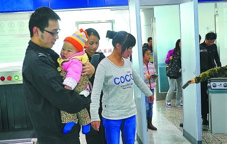 重慶江北機(jī)場安檢門通道工作員抱小孩兒助乘客安檢[圖]